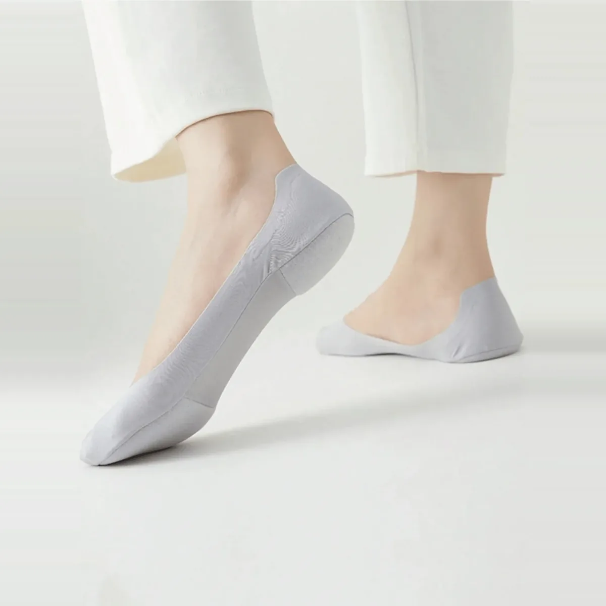 Grey no-show sock worn on a foot in motion