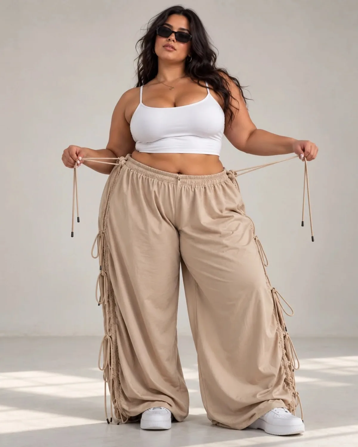 Modelo curvy con el pantalón oversize camel ajustando los cordones de la cintura